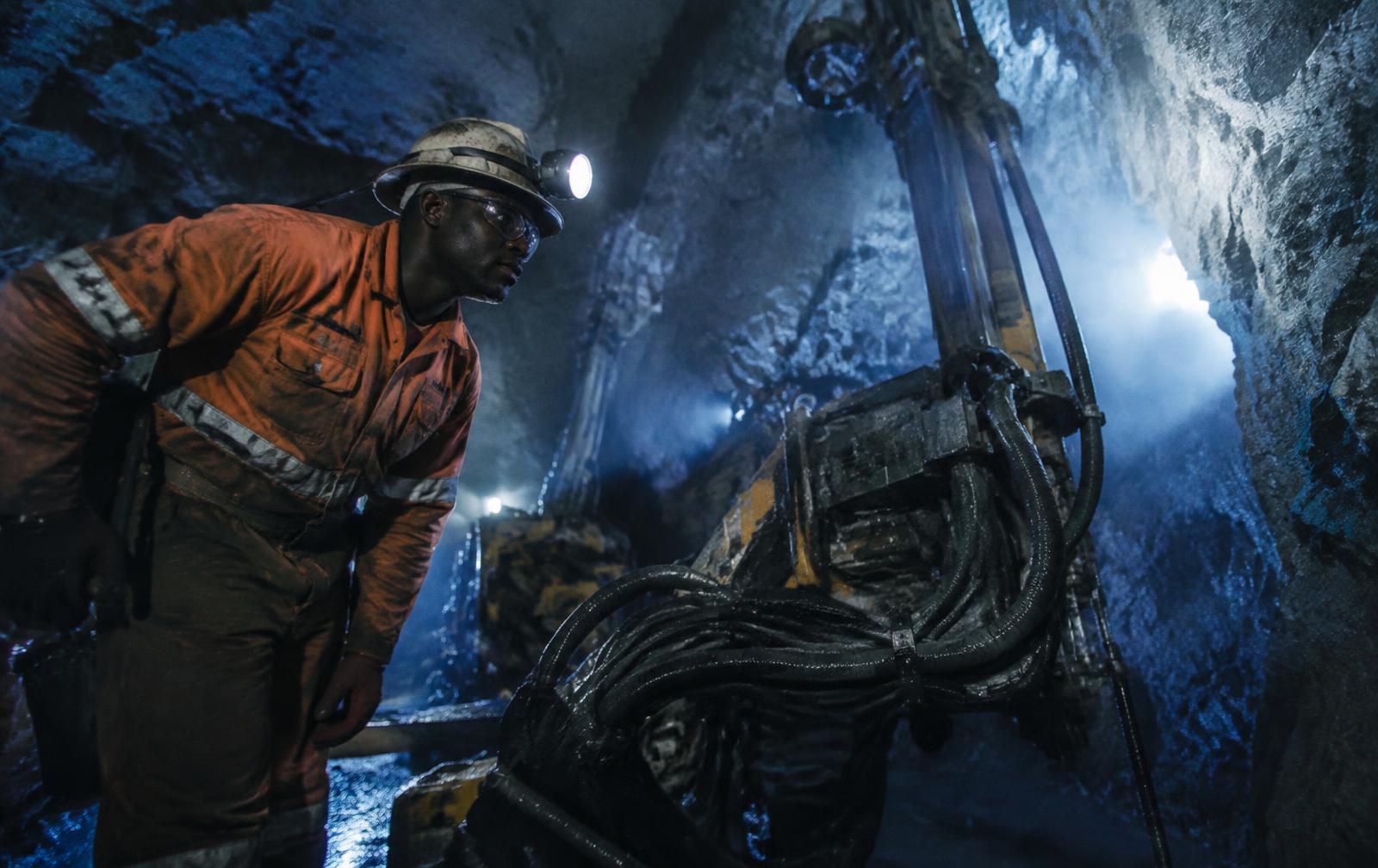 Miner inspecting a rock drill rig underground